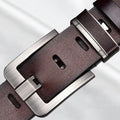 Brown leather belt with silver buckle on a light gray background